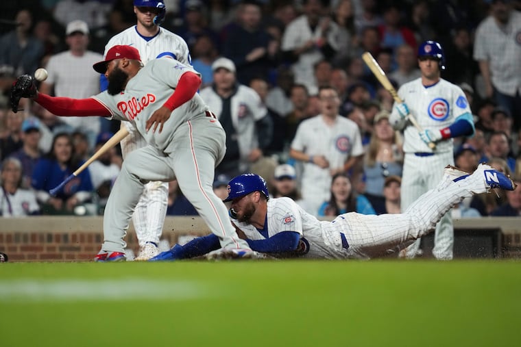 Cubs' Michael Busch (right) scores on a wild pitch from Phillies pitcher José Alvarado during the eighth inning.