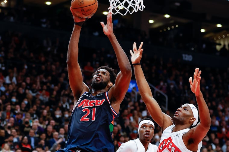 Sixers center Joel Embiid lays-up the basketball against Toronto Raptors forward Chris Boucher and forward Precious Achiuwa during game three of the first-round Eastern Conference playoffs on Wednesday, April 20, 2022 in Toronto.
