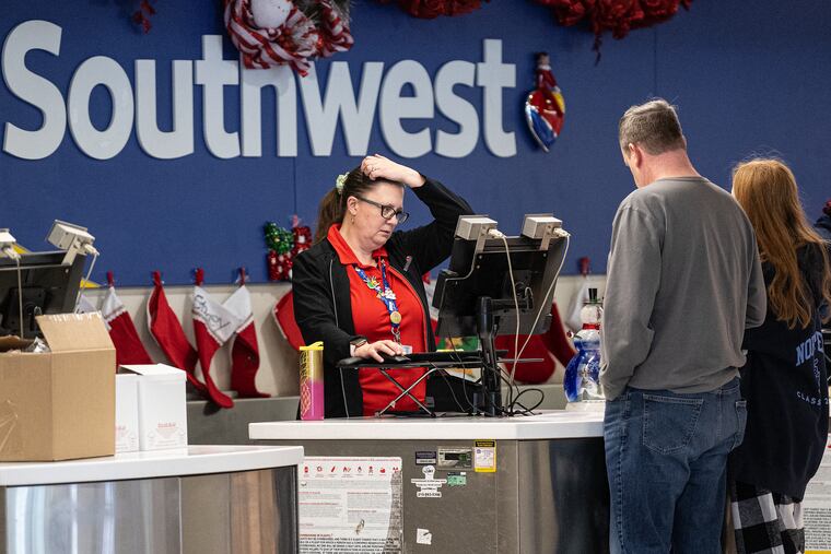An airport ticket agent is shown on Tuesday at the Southwest Airlines terminal at Philadelphia International Airport. Southwest Airlines continues canceling flights as New Year holiday approaches.