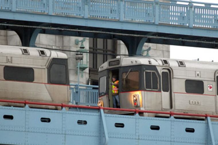 A worker on the stalled train (right) guides a working PATCO train (left) as it tries to couple and pull a disabled train back to New Jersey from the middle of the Ben Franklin Bridge on Friday. (File Photo / Staff)