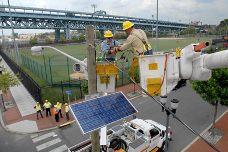 Linemen Terry Lane (left) and Mike Gregory install a solar panel at Linden Street and Delaware Avenue in Camden as part of Public Service Electric and Gas’s “Solar 4 All” project. (April Saul / Staff Photographer)