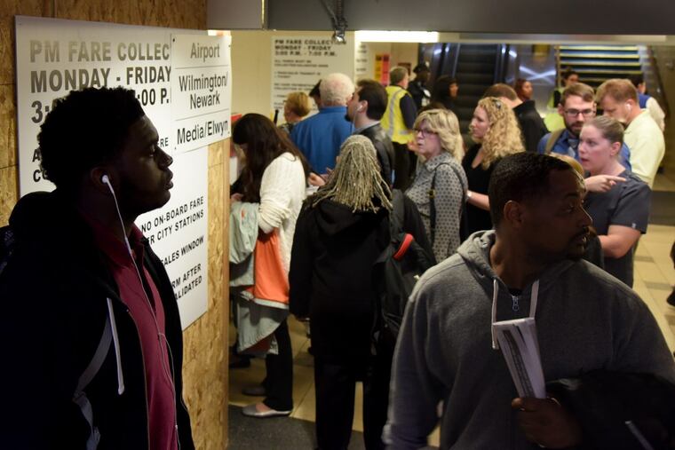 Adonis Davis (left) waits for his Sharon Hill train with other commuters at 30th Street Station during evening rush hour on the third day of the 2016 SEPTA strike. The sign behind Davis explains the fare collection procedure put in place in August 2016, when SEPTA started checking tickets before passengers boarded trains.