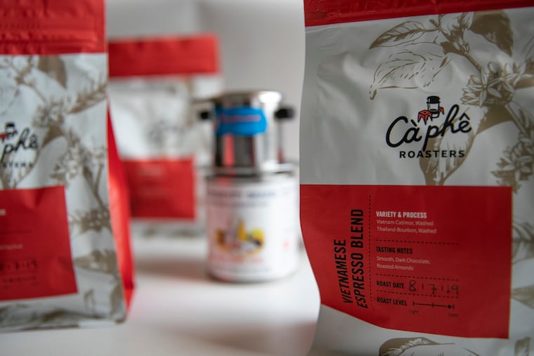 Locally roasted Vietnamese coffee from Càphê Roasters is photographed next to condensed milk and a Vietnamese "phin" coffee maker.