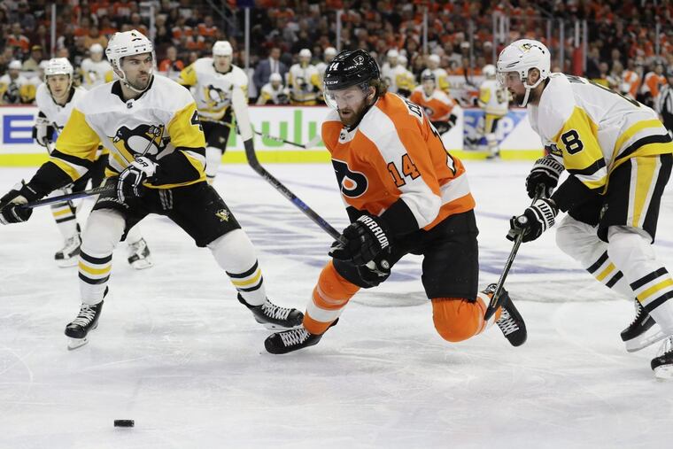 Flyers center Sean Couturier goes after the puck against Penguins defensemen Justin Schultz (left) and Brian Dumoulin in Game 3 on Sunday. Couturier limped off the ice into the dressing room after being injured during practice Tuesday. YONG KIM / Staff Photographer