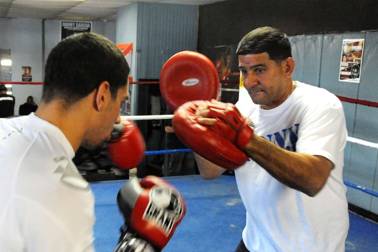 Angel Garcia sports pads for his son Danny to hit as they prepare for Saturday's title defense against Erik Morales.