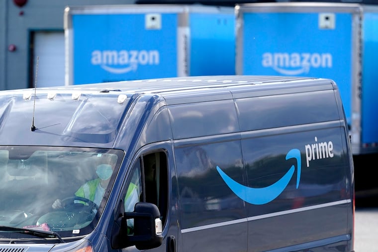 An Amazon Prime logo appears on the side of a delivery van as it departs an Amazon warehouse.