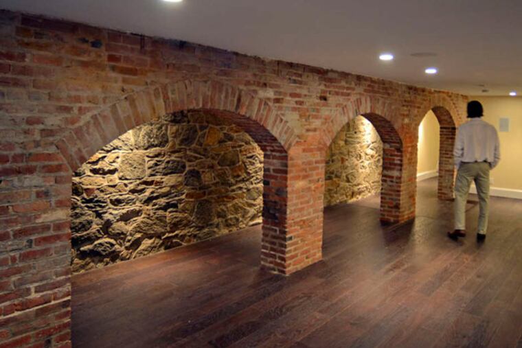 Developer Marc Shaw walks among the restored original walls in the basement of 332 Spruce St., one of two 1830s houses that had been turned into apart-ments in the '50s.