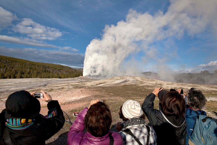 In this May 21, 2011, file photo, tourists photograph Old Faithful erupting on schedule late in the afternoon in Yellowstone National Park, Wyo. A woman has suffered burns after falling into a thermal feature at Yellowstone National Park, which is closed because of the coronavirus pandemic. Officials say she was reportedly backing up while taking photos Tuesday, May 12, 2020, and fell into a hot spring or hole where hot gases emerge near Old Faithful geyser.