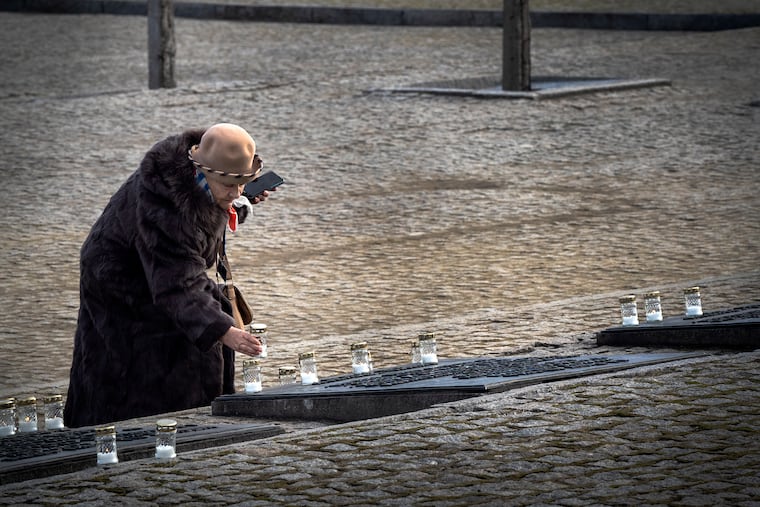 A Holocaust survivors places a candle on a monument at Auschwitz-Birkenau to remember those who were killed in the Holocaust. Hundreds of Holocaust survivors join delegates from around the world at Auschwitz-Birkenau, the former Nazi death camp, in Oświęcim, Poland, on January, 27, 2020, the 75th anniversary of the camps liberation and International Holocaust Remembrance Day.