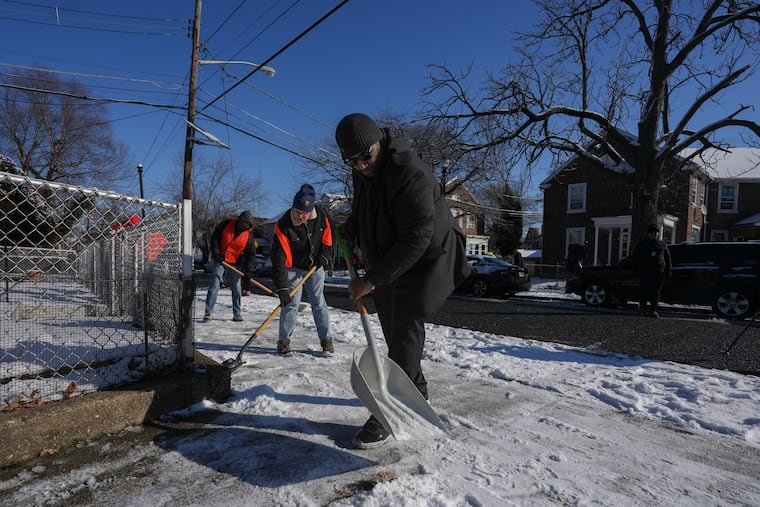 Pastor Daniel Brown, left, from Freedom Worship Assembly Chuch, shovels snow at Fairview Village in Camden, New Jersey.