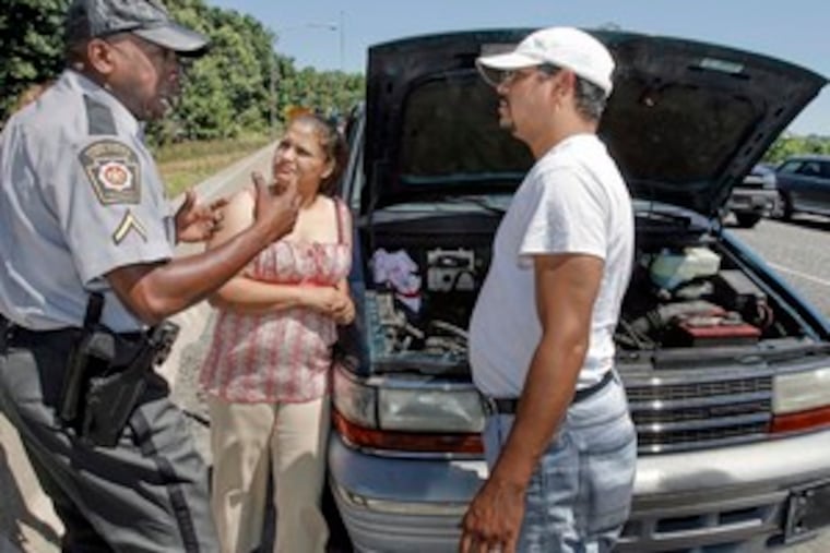 On the Schuylkill Expressway near Girard Avenue, State Trooper Tie Bradford (left) helps out stranded motorists Naomi and Jose Class from Reading. They were heading to the airport when their car broke down; Bradford took Naomi Class, her children and grandmother to the airport to meet her grandfather because a wrecker would not have arrived in time.