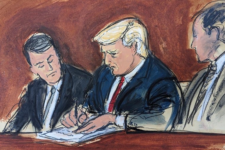 Former President Donald Trump, center, flanked by his defense attorneys, signs his bond in federal court on June 13, 2023, in Miami.