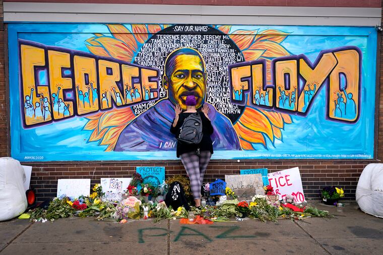 Damarra Atkins pays respect to George Floyd at a mural at George Floyd Square in Minneapolis, April 23, 2021.