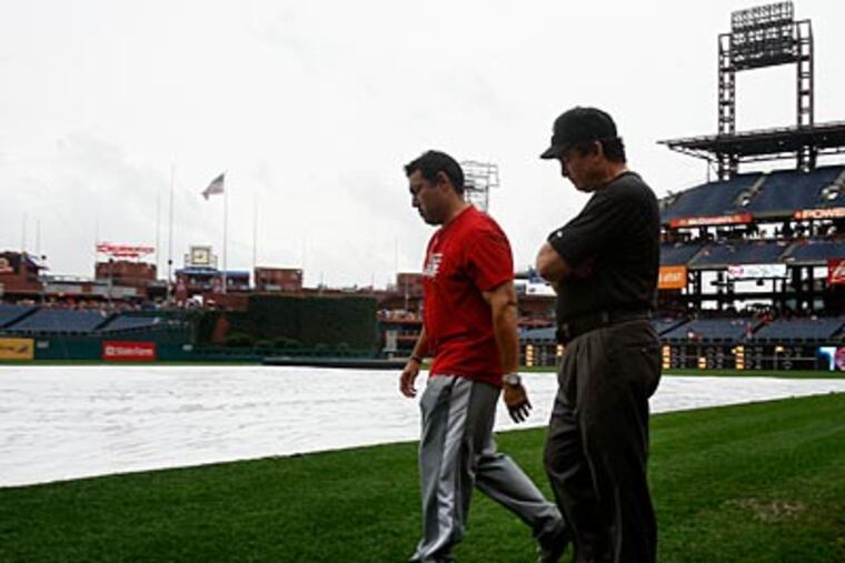 Ruben Amaro Jr. and umpire Ed Rapuano walk on the field before Saturday's game was postponed. (Ron Cortes/Staff Photographer)