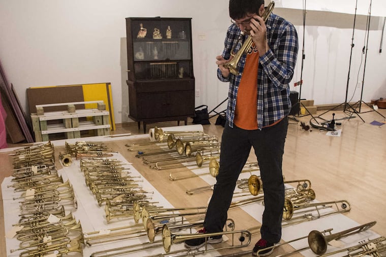 Connor Przybyszewski, 28, a Drexel grad and a professional musician living in West Philly, tries out a trombone in tTemple Contemporary, at Tyler School of Art as part of the Symphony for a Broken Orchestra exhibit.