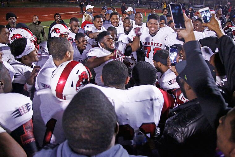 Imhotep Charter players huddle in celebration around tight end Naseir Upshur (arms raised) after their championship victory over Archbishop Wood. Imhotep won, 20-14, Saturday (11/28/15) in the District 12 Class AAA football final at Northeast High. (LOU RABITO / Staff)
