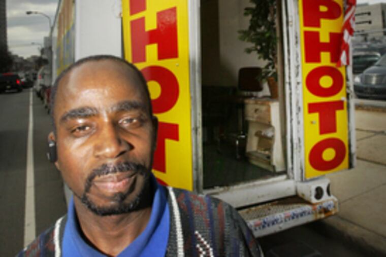 The Rosa Photo truck (at left), with owner Rosa de Braun in 2002, was a mainstay on Callowhill Street near the immigration office until Thursday, when police hauled it away. Joseph Wulu Doe (above), at his photo truck yesterday, now has the sole street studio.