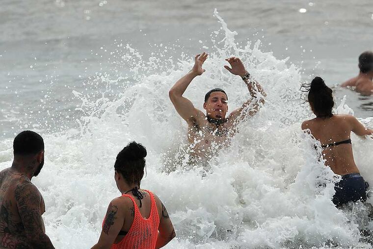 The waves were rolling in along the Ocean City beach as Ray Diaz, 24, from the Feltonville neighborhood of Philadelphia and his friend Isis (cq) Rodriguez, 20, from Juaniata, wade into the water on Labor Day 2014. (Clem Murray / Staff Photographer)