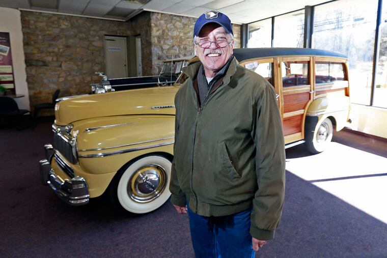 Rodger Paisley with a 1947 Mercury "Woody" station wagon, among cars on the auction block Saturday. His job, he said, is to encourage bidding.