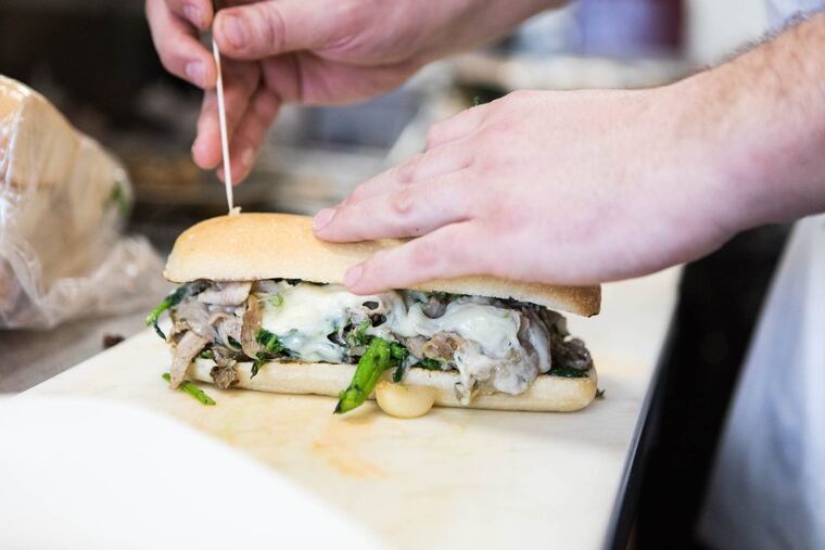 Chef Josh Lawlor of the Farm and Fisherman tavern in Horsham, Pa., sticks a toothpick in a finished Veteran’s Stadium roast pork sandwich.