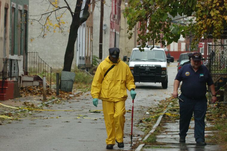Police look for clues along the 1800 block of Etting Street, where paroled felon Lamont Norman, 32, was killed after a chase that began when he shot at officers late Thursday night.