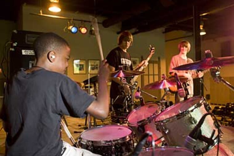 Rock & Roll After School, a kids' music school in Phoenixville, opened last month in a brand-new facility. Isaiah Weatherspoon, left, drums, as twin brothers Mickey and Blake McClimon join in. (Ed Hille / Staff Photographer)