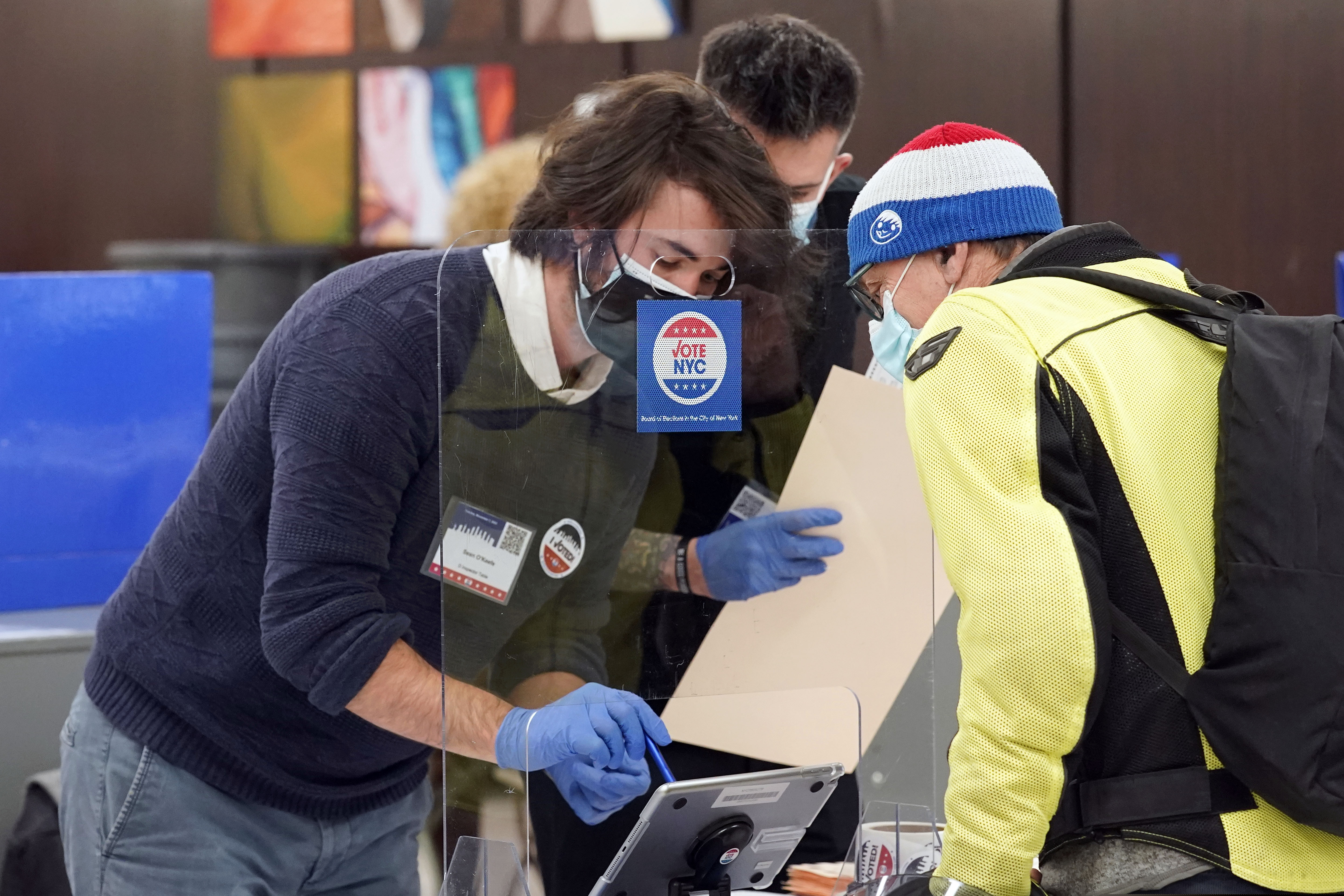Poll workers assist a voter on Election Day at Frank McCourt High School, on New York's Upper West Side. Poll workers in some states who came in contact with voters on Election Day are now reporting they have tested positive for the coronavirus despite painstaking efforts to secure election sites. To be sure, the cases cannot be tied definitely to polling places.