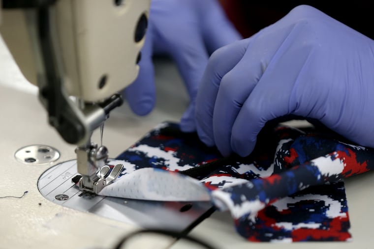 Nga Nguyen sews cloth face masks at the Boathouse Sports factory in North Philadelphia on Tuesday, April 14, 2020. Manufacturing has been hard hit in Philadelphia, but clean energy presents an opportunity, write Brendan Boyle and Jacquelyn Bonomo.