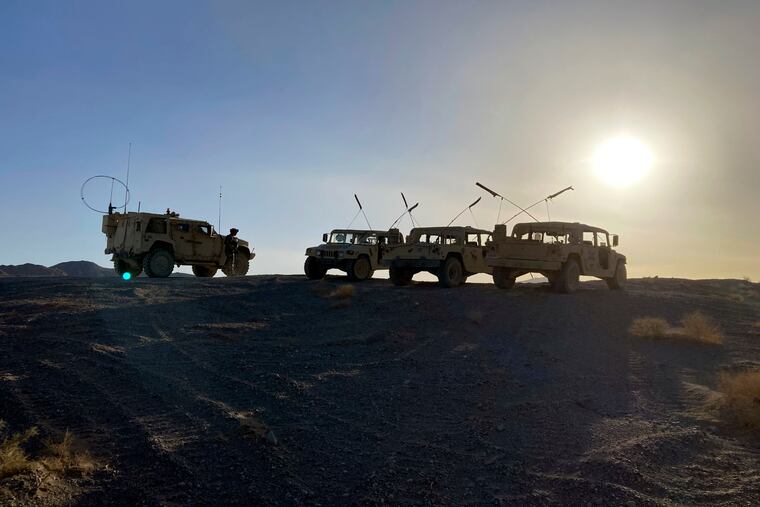 Army vehicles on the ridge, as soldiers from the 2nd Brigade, 1st Cavalry Division, prepare to attack the enemy in the town nearby, during an early morning training exercise at the National Training Center at Fort Irwin, Calif., April 12, 2022.