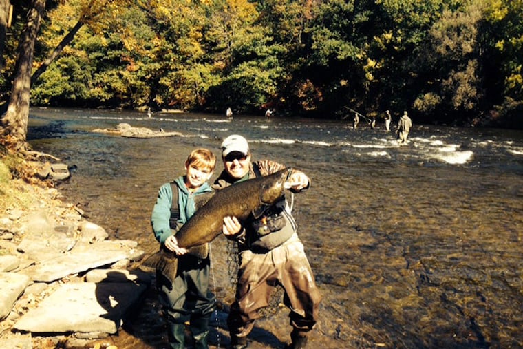 Arthur LaBan, 12, proudly holds the 28-pound river salmon he caught on the family adventure, joined by guide Tommy Basciani. (MARK PAOLI)