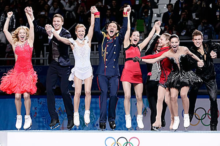 The Russian team jump onto the podium during the flower ceremony after placing first in the team figure skating competition. (Bernat Armangue/AP)