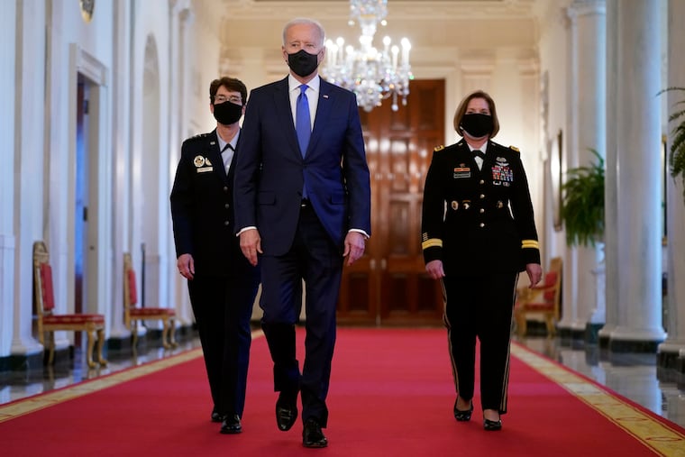 President Joe Biden walks with U.S. Air Force Gen. Jacqueline Van Ovost, left, and U.S. Army Lt. Gen. Laura Richardson before speaking at an event to mark International Women's Day.