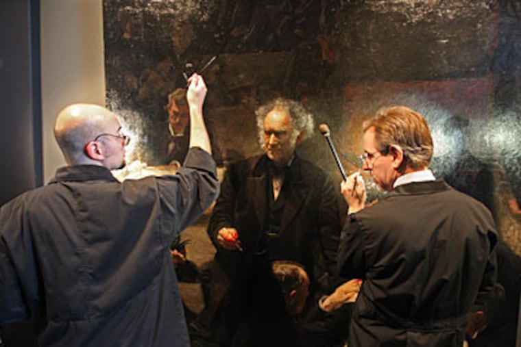 Allen Kosanovich and Mark S. Tucker (right) work on Thomas Eakins’ “The Gross Clinic,” which temporarily shares a room at the Philadelphia Museum of Art’s Perelman Building with a Rembrandt. (MICHAEL BRYANT / Staff Photographer)