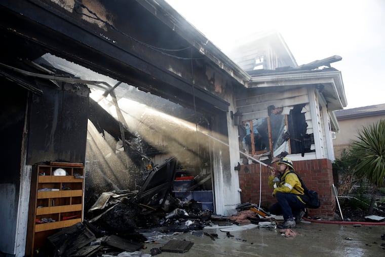 Calib Willis of the Los Angeles County Fire Department hoses down a smoldering residence destroyed by a wildfire Friday, Oct. 25, 2019, in Santa Clarita, Calif.