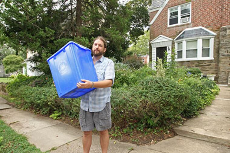 Kevin Stutler holds up the Blue City Recycle bin he left out on the curb the day he ws cited for not recycling. (Michael Bryant / Staff Photographer)