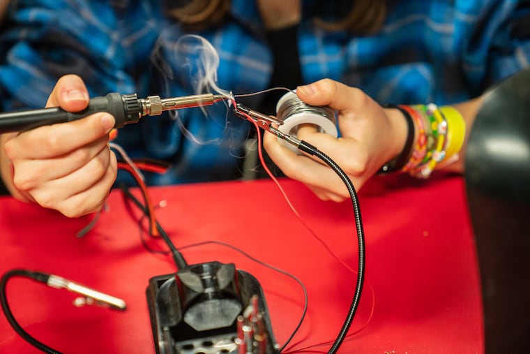 Team member Iris McLeary, Impact Coordinator, demonstrates a soldering technique at Central High School in Philadelphia, on Friday, April 28, 2023. The Central High RoboLancers were at the World Robotic Championship in Houston last week where they beat out nearly 100 other teams to win the Impact Award for the work the team has done in spreading robotics to hundreds of kids around the city.