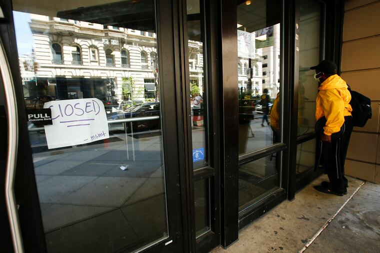 A pedestrian looks inside the closed Wawa on Broad and Walnut Streets in Center City earlier this month. The Flagship Wawa closed due to the pandemic.