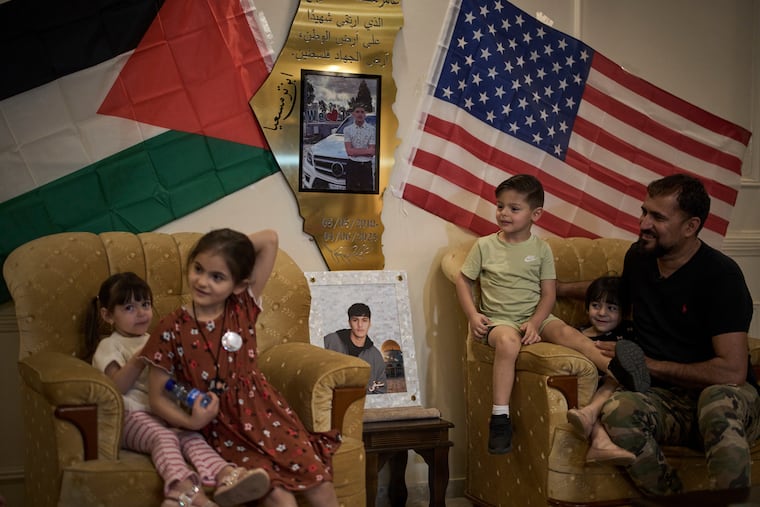 Mohammed Rabee, 48, sits with his grandchildren beside photos of his 14-year-old son, Amer Rabee, a New Jersey boy who was killed by Israeli soldiers while in a roadside thicket in the West Bank in April.