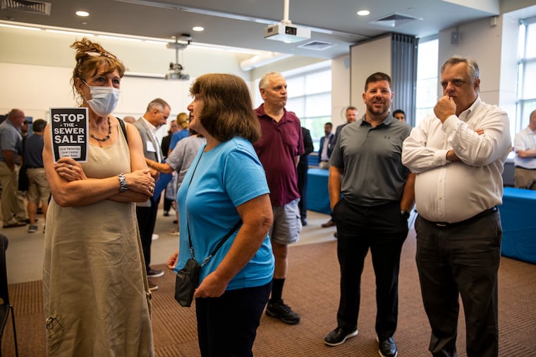 Kara Raymond, of Doylestown, holds a “Stop the Sewer Sale” pamphlet during an open house question-and-answer session held by the Bucks County Water and Sewer Authority in Perkasie last month.