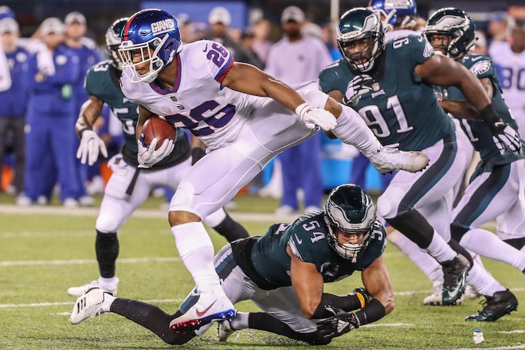 The Giants Saquon Barkley, left, jumps up to avoid the tackle of Eagles Kamu Grugier-Hill, center, for a long gain in the second quarter of Thursdays game. MICHAEL BRYANT / Staff Photographer
