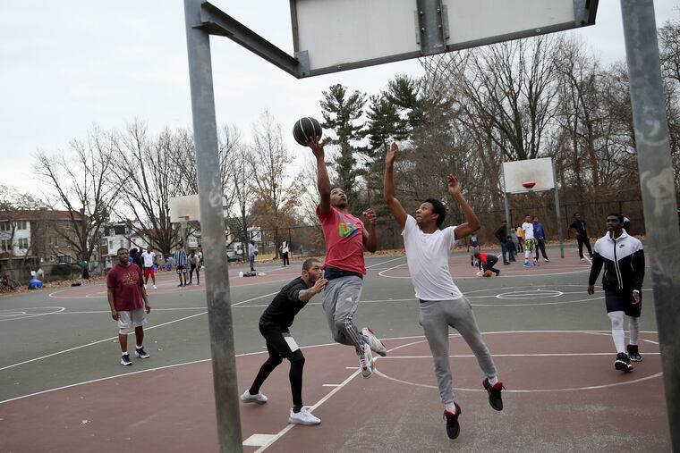 Naheem Williams (center in red) attempts a layup past Quinzel Tabron, (center left in black), and Amir Ford during a pickup game of basketball at Cobbs Creek Park in West Philadelphia on Saturday.