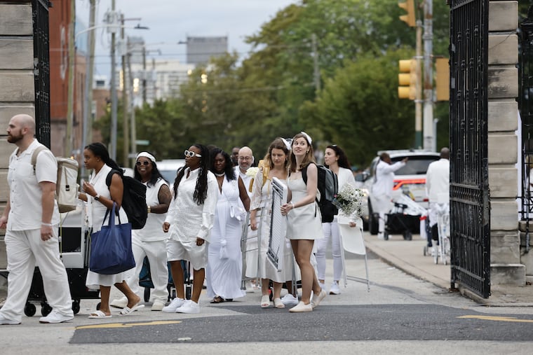 People arrive with their tables and chairs for the 13th annual Le Diner en Blanc, an annual all-white party, taking over Girard College Thursday, Aug. 21, 2025, in Philadelphia.