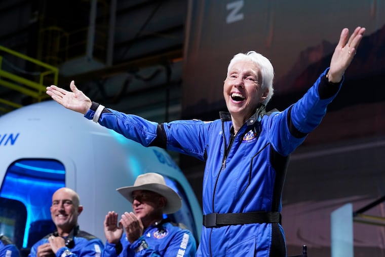 Wally Funk (right) describes her flight experience as Mark Bezos (left) and Jeff Bezos (center) applaud in the spaceport near Van Horn, Texas, July 20, 2021. She died Wednesday at age 87.