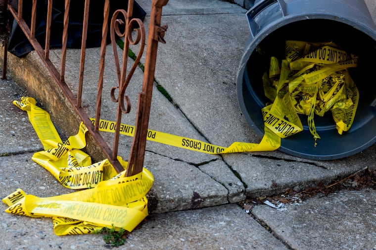 Discarded crime scene tape remains on the 2300 block of Jackson Street in South Philadelphia Sunday following a shooting there Saturday night that pushed the city's homicide total this year to beyond 400.