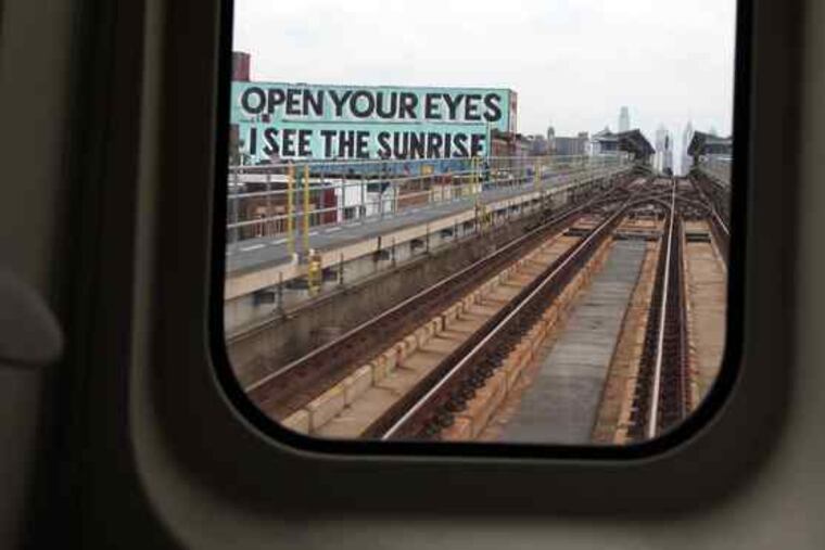 One of the roof murals can be seen from the El. Artist Steve Powers and a team of painters are working on the collection that stretches along the Market-Frankford El in West Philadelphia.