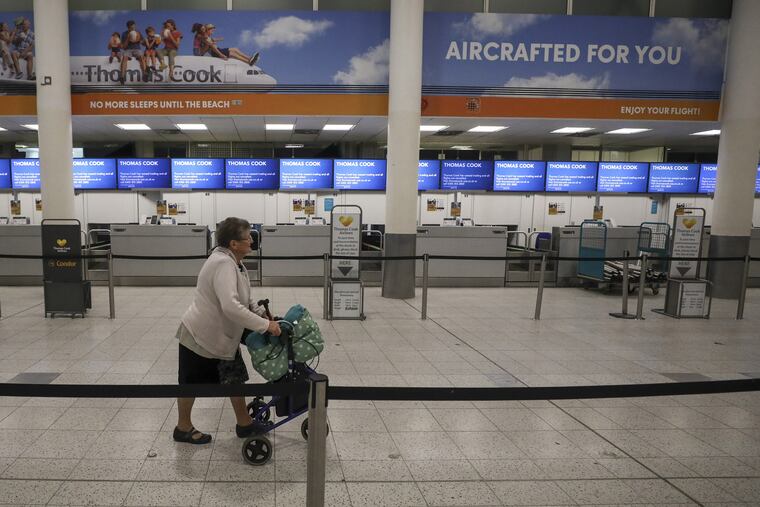 At London Gatwick Airport, a woman walks past closed check-in desks for Thomas Cook on Monday, Sept. 23.