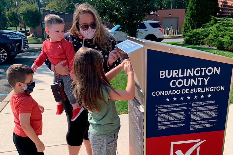 Nicole Flaherty, top, stands with her kids as her 7-year-old daughter Madelyn places the ballot in the Burlington County ballot box in Cinnaminson.