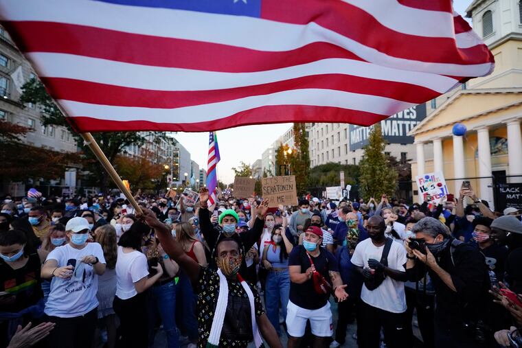 People gather in Black Lives Matter Plaza to celebrate president-elect Joe Biden's win over Pres. Donald Trump to become the 46th president of the United States, Saturday in Washington. The results of the election show a very divided country.