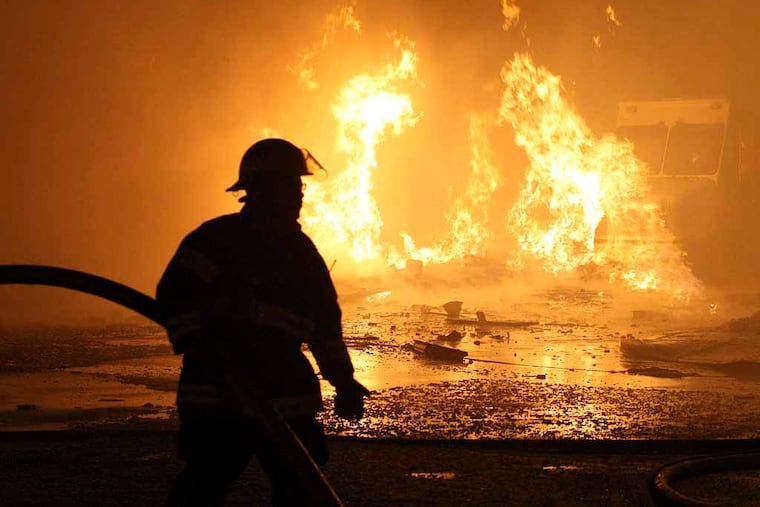Gas Main Fire at 6900 Torresdale Avenue, Tuesday, January 18, 2011. A firefighter moves a hose line at the scene. One gas worker was killed two were injured. ( Steven M. Falk / Staff Photographer )