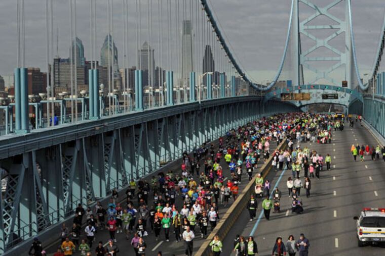 Runners and walkers cross the Ben Franklin Bridge during a benefit event. Officials say that up to 100,000 pedestrians will cross the bridge each day of Pope Francis’ visit — and that each will be screened. (APRIL SAUL / File Photograph)